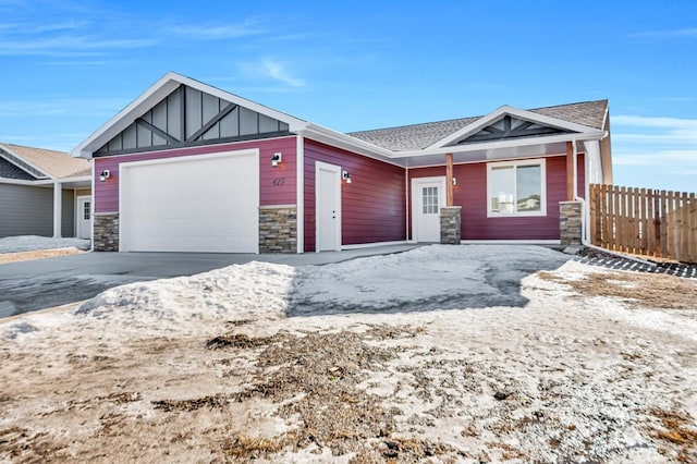 view of front of property featuring an attached garage, fence, stone siding, concrete driveway, and board and batten siding