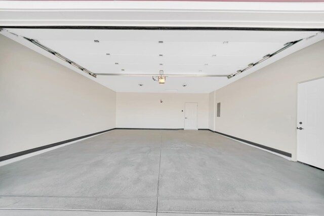 garage featuring a garage door opener, electric panel, and baseboards