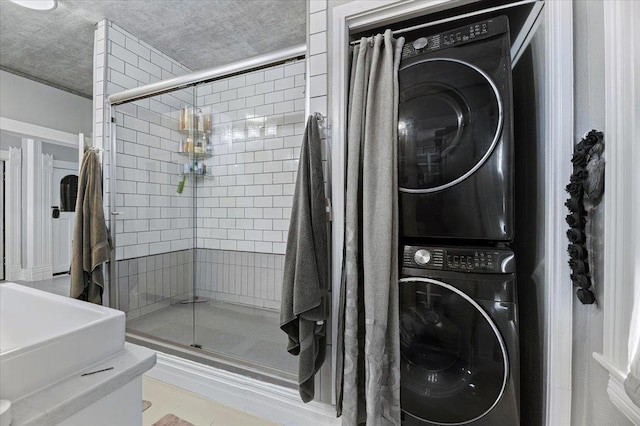 bathroom featuring stacked washer / drying machine, a textured ceiling, and a shower with shower door