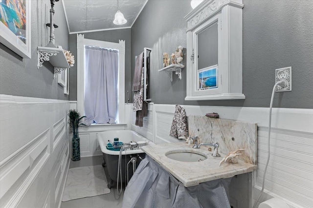 bathroom with lofted ceiling, sink, and a tub