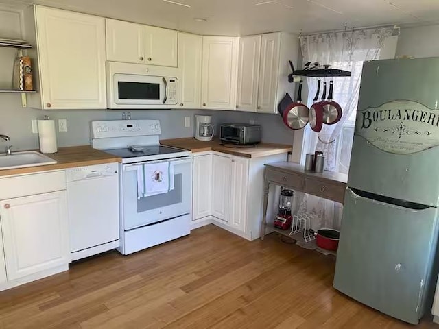 kitchen with sink, white appliances, light hardwood / wood-style floors, and white cabinets