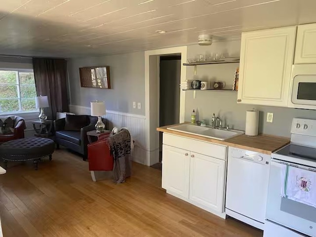 kitchen featuring white cabinetry, sink, white appliances, and light hardwood / wood-style floors