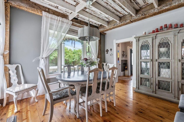 dining space with beam ceiling and light hardwood / wood-style flooring