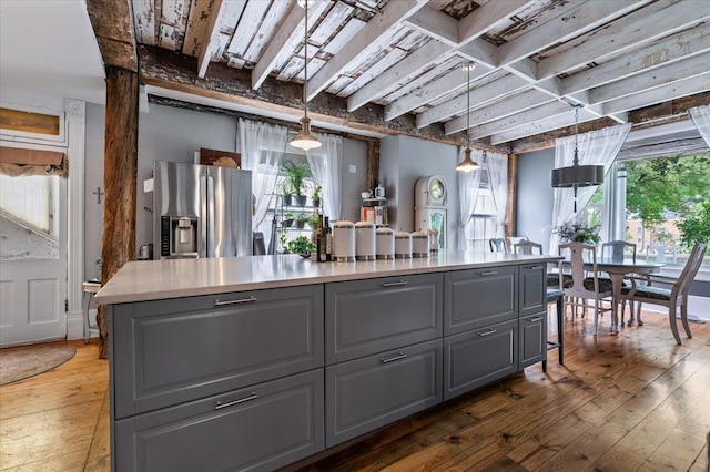 kitchen featuring gray cabinetry, decorative light fixtures, stainless steel fridge, and a center island