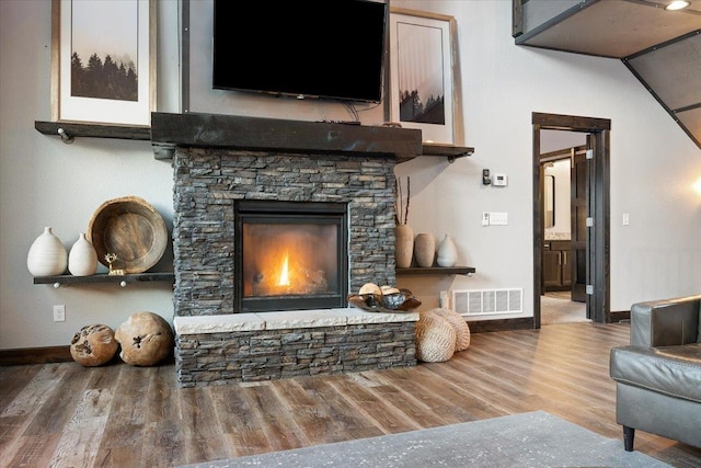 living room with hardwood / wood-style flooring and a stone fireplace