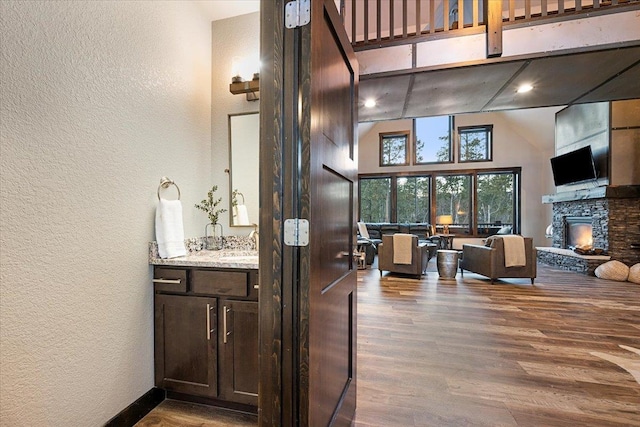 bathroom featuring vanity, a fireplace, wood-type flooring, and a high ceiling