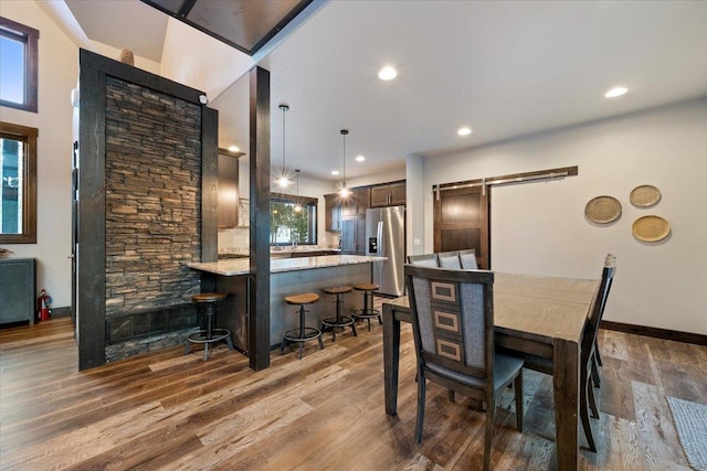 dining space with a barn door and dark hardwood / wood-style flooring