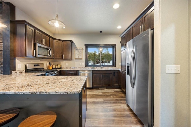 kitchen featuring hanging light fixtures, appliances with stainless steel finishes, a breakfast bar, and kitchen peninsula