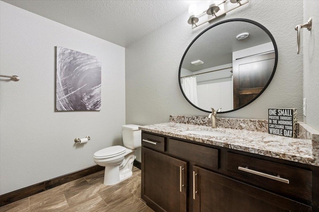 bathroom featuring vanity, a textured ceiling, toilet, and walk in shower