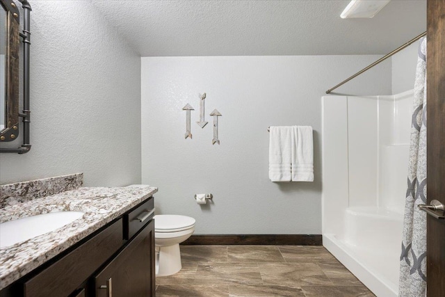 bathroom with walk in shower, vanity, toilet, and a textured ceiling