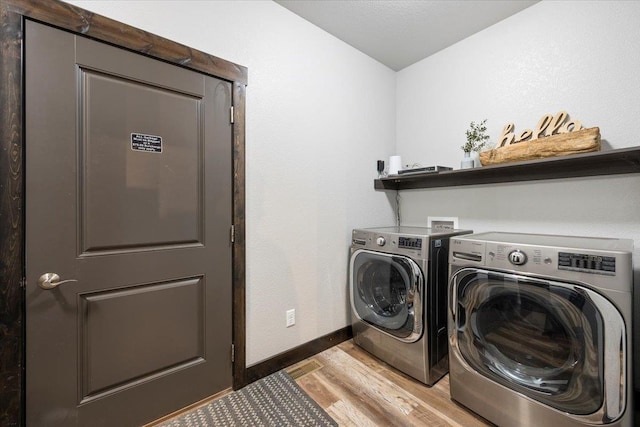 clothes washing area featuring washing machine and clothes dryer and light wood-type flooring