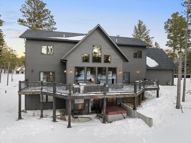 snow covered house featuring a hot tub and a deck