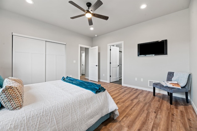 bedroom with ensuite bath, hardwood / wood-style floors, ceiling fan, and a closet