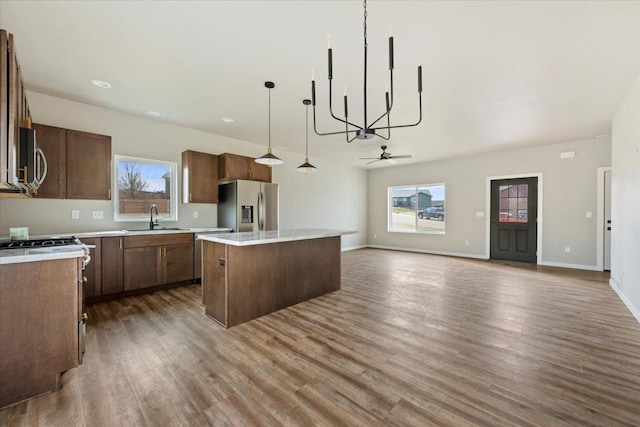 kitchen with a kitchen island, wood-type flooring, sink, hanging light fixtures, and stainless steel appliances