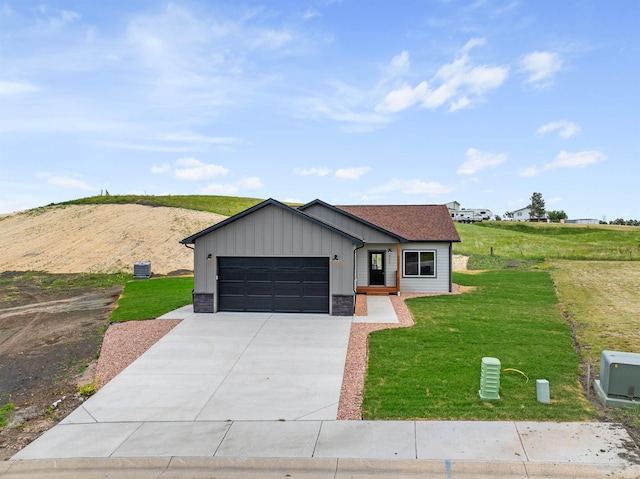 view of front of property featuring a garage, central AC, and a front lawn