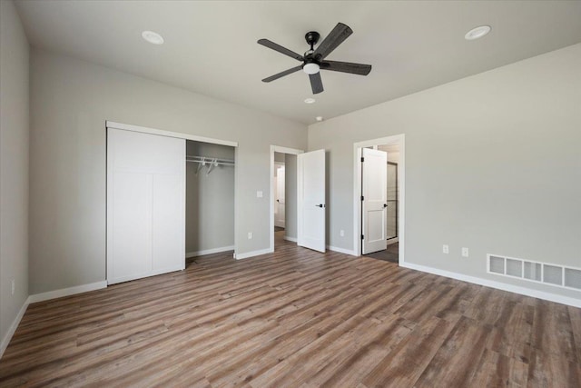 unfurnished bedroom featuring hardwood / wood-style flooring, ensuite bath, ceiling fan, and a closet