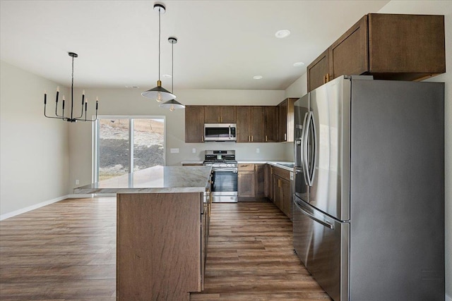 kitchen with pendant lighting, hardwood / wood-style floors, a center island, and appliances with stainless steel finishes