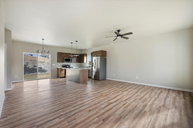 kitchen with hanging light fixtures, a kitchen island, a healthy amount of sunlight, and appliances with stainless steel finishes