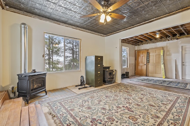 interior space with ornamental molding, a wood stove, and ceiling fan