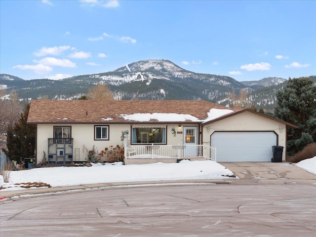 ranch-style home with a porch, a garage, and a mountain view