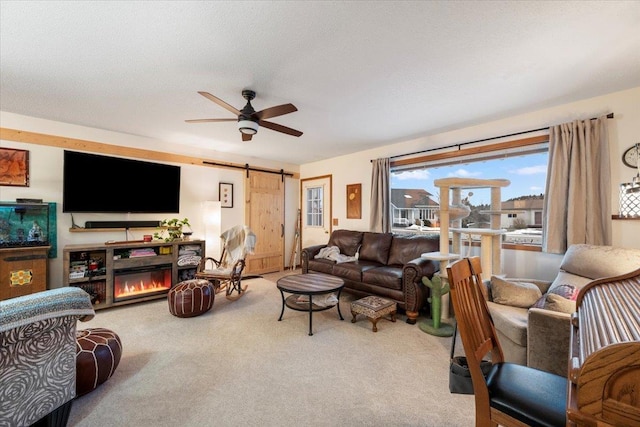 carpeted living room featuring a textured ceiling, a barn door, and ceiling fan