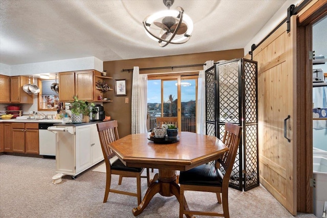 carpeted dining area featuring sink, a barn door, and a textured ceiling