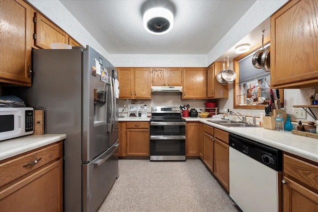 kitchen with appliances with stainless steel finishes, sink, and a textured ceiling