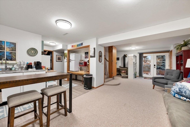 interior space featuring french doors, sink, a textured ceiling, white fridge, and light colored carpet