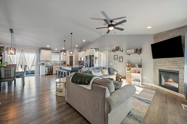 living room featuring lofted ceiling, a fireplace, dark hardwood / wood-style floors, and ceiling fan