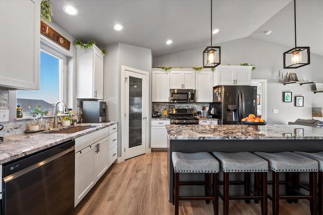 kitchen with light stone counters, decorative light fixtures, white cabinets, and appliances with stainless steel finishes