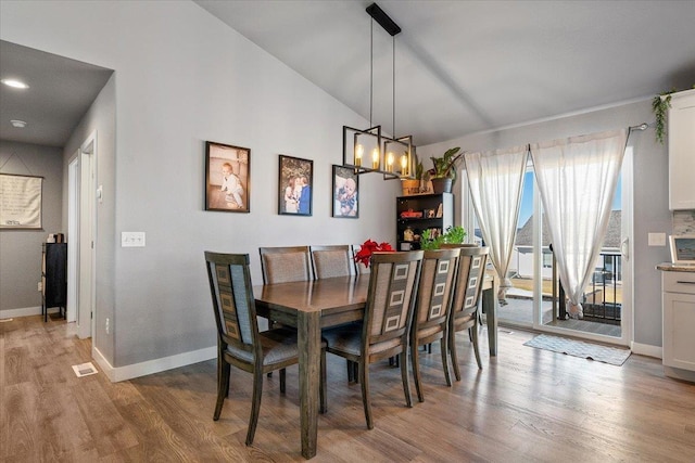 dining area with vaulted ceiling, wood-type flooring, and a chandelier