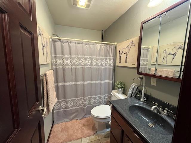 bathroom featuring walk in shower, tile patterned floors, vanity, and toilet