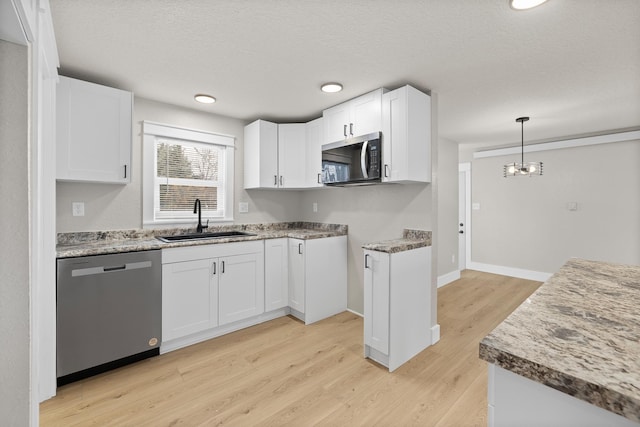 kitchen featuring white cabinets, hanging light fixtures, stainless steel appliances, and sink