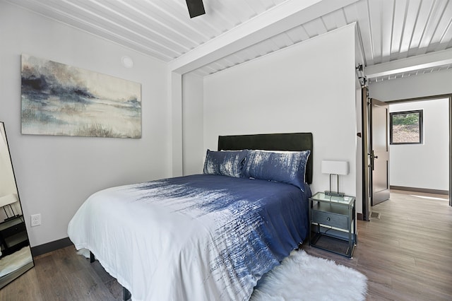 bedroom with ceiling fan, wood-type flooring, and beam ceiling