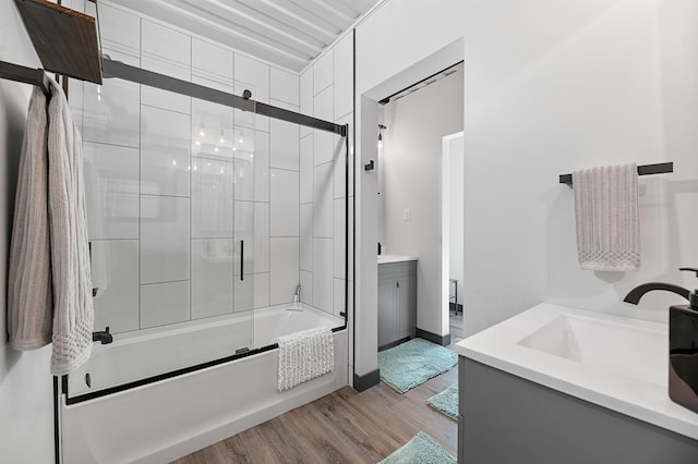 bathroom with hardwood / wood-style flooring, vanity, and bath / shower combo with glass door