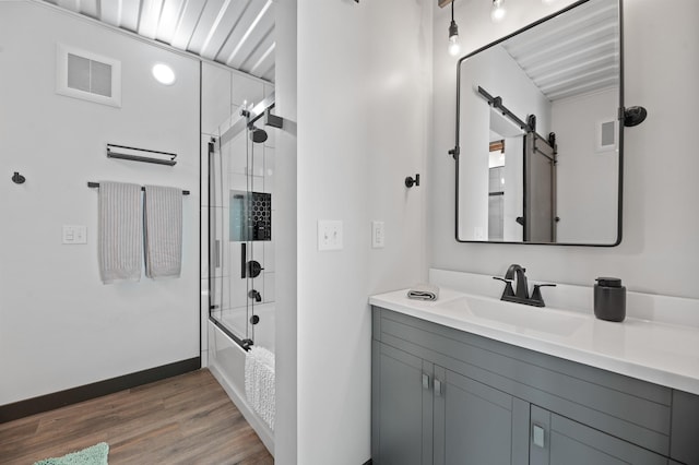 bathroom with vanity, hardwood / wood-style floors, and bath / shower combo with glass door