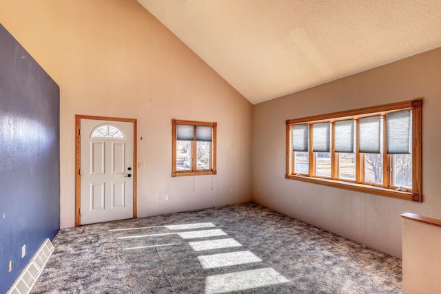 carpeted entryway featuring plenty of natural light and high vaulted ceiling