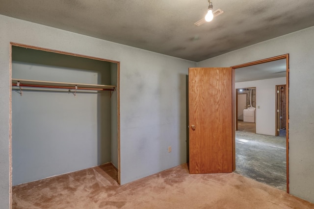 unfurnished bedroom with washer / dryer, carpet, and a closet