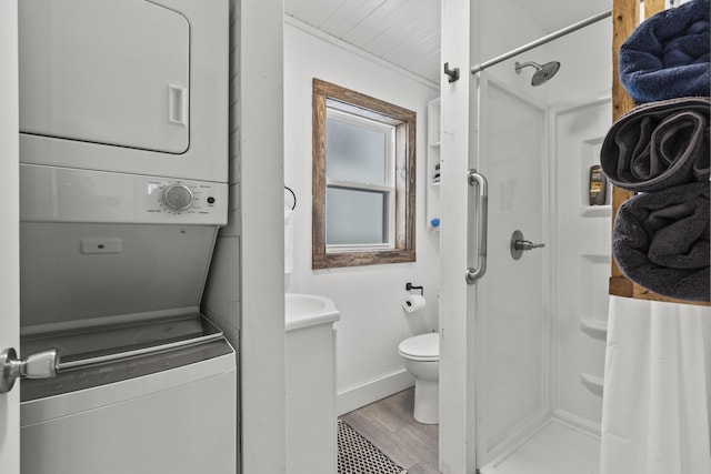 bathroom featuring stacked washer / dryer, a shower, wood-type flooring, and toilet