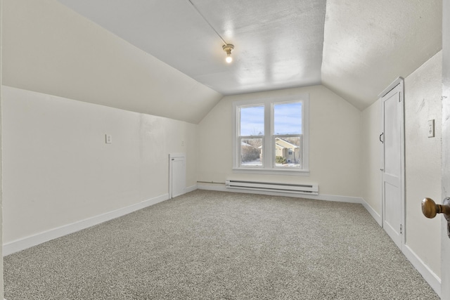 additional living space featuring lofted ceiling, a textured ceiling, carpet, and a baseboard heating unit