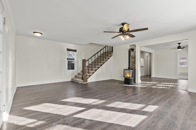 unfurnished living room featuring dark hardwood / wood-style flooring, ceiling fan, and a wood stove