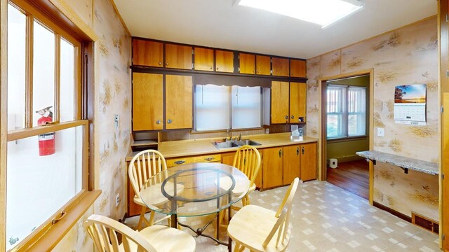 133 Pine Ave, Hill City, SD 57745 - kitchen with wallpapered walls, light countertops, a sink, brown cabinetry, and light floors