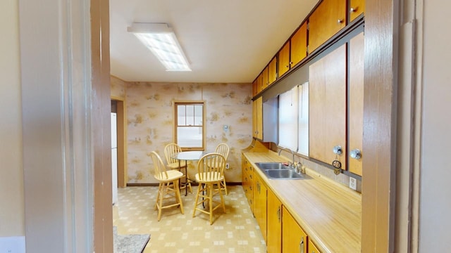 133 Pine Ave, Hill City, SD 57745 - kitchen with a sink, light countertops, wallpapered walls, baseboards, and light flooring