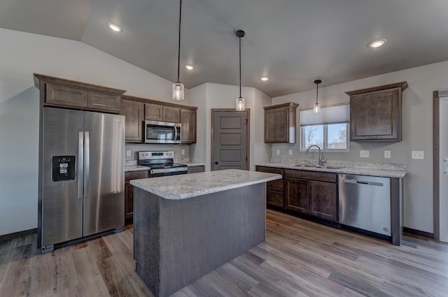 kitchen featuring sink, light hardwood / wood-style flooring, appliances with stainless steel finishes, a kitchen island, and pendant lighting