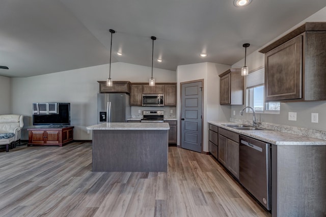 kitchen featuring sink, stainless steel appliances, light hardwood / wood-style floors, a kitchen island, and decorative light fixtures