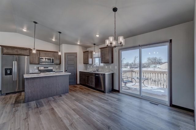 kitchen featuring sink, stainless steel appliances, a center island, decorative light fixtures, and light wood-type flooring