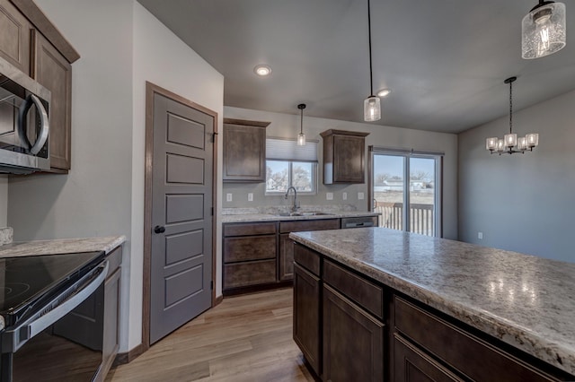 kitchen with hanging light fixtures, dark brown cabinets, light hardwood / wood-style flooring, and black / electric stove