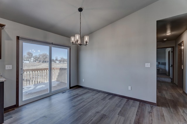 unfurnished dining area featuring a notable chandelier and dark hardwood / wood-style floors