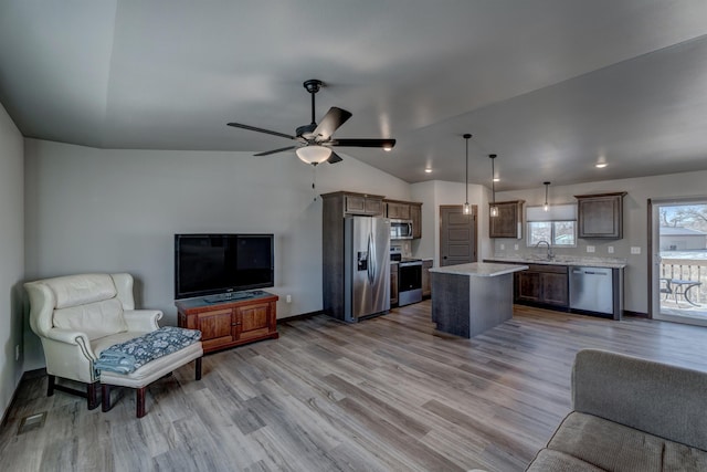 living room featuring vaulted ceiling, ceiling fan, sink, and light hardwood / wood-style flooring