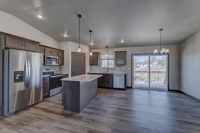 kitchen featuring a kitchen island, decorative light fixtures, lofted ceiling, stainless steel appliances, and dark brown cabinets